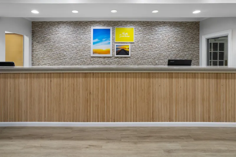 Front desk with a wood-slat counter and stone wall behind it